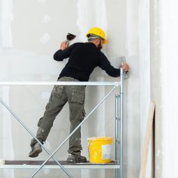Interior construction, worker plastering gypsum board wall.